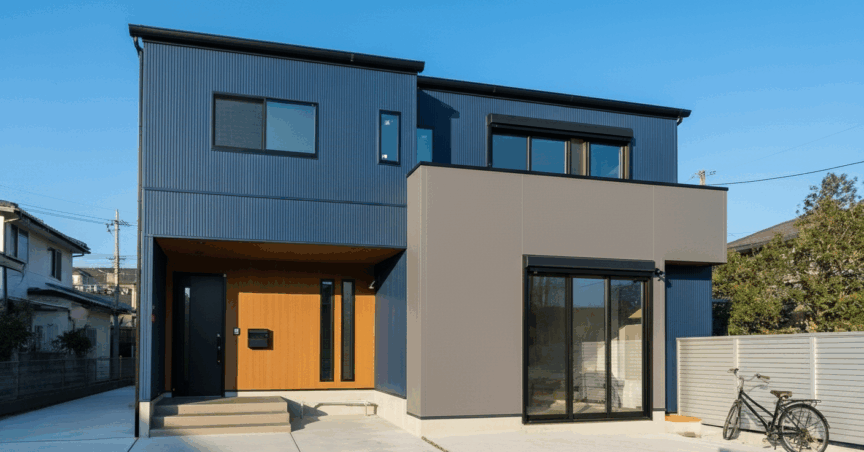 外壁にネイビーとグレー、玄関周りに木目調を使用した家の写真